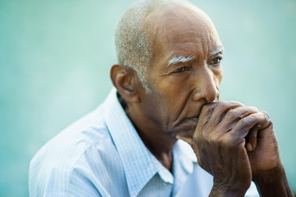 elderly ethnic man with hands together thinking