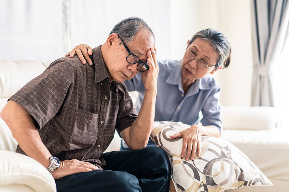 older asian male being comforted by old asian woman